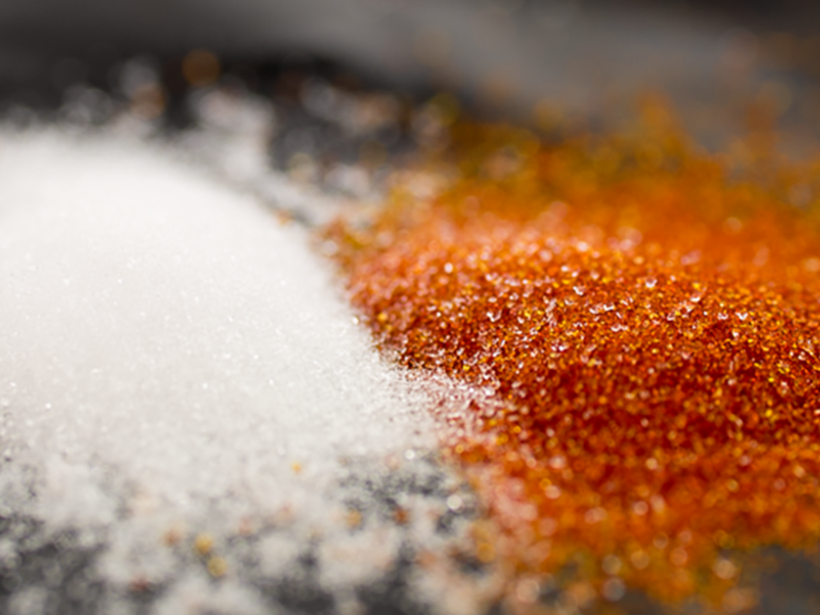 Close-up view of two contrasting resins side by side - white ionic exchange resin and orange hydrophobic resin - demonstrating the different media types used in selective extraction processes with the SpinChem RBR