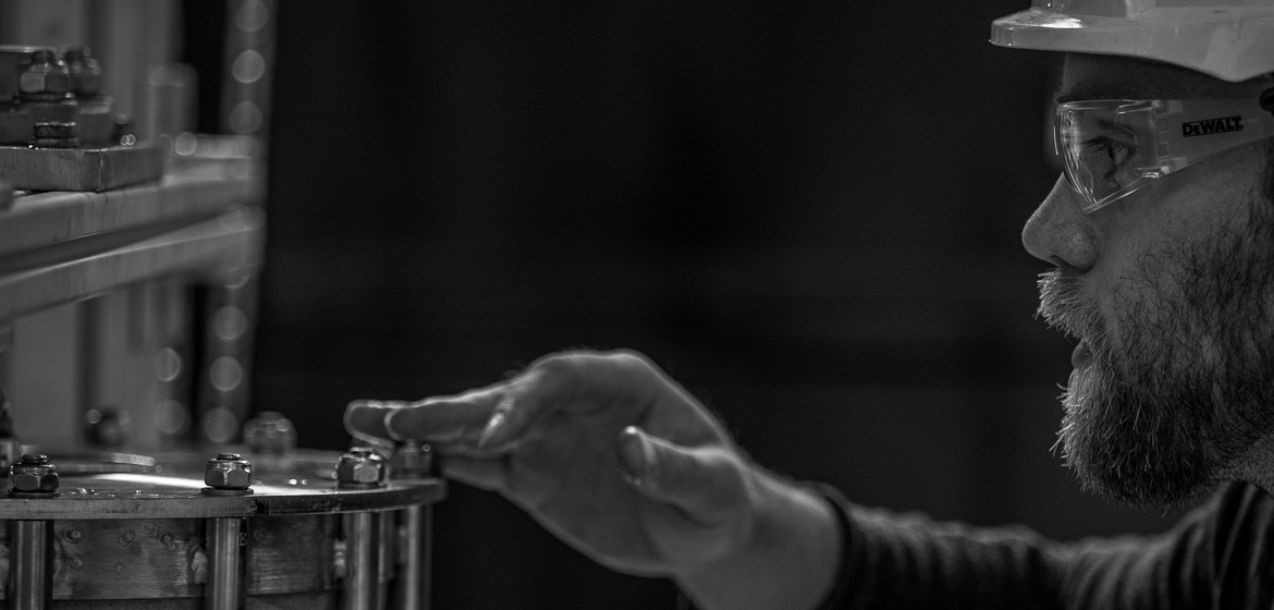 Person in PPE inspecting a rotating bed reactor.