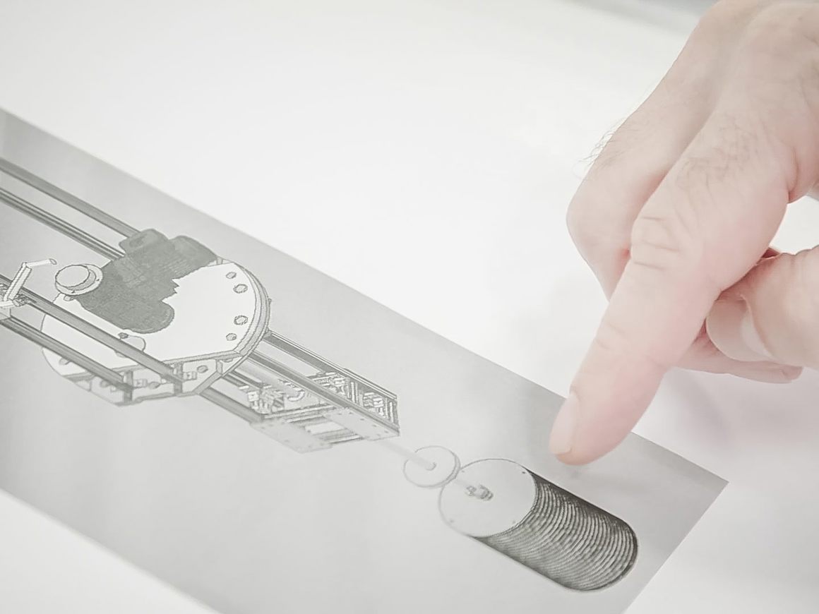 Close-up of a hand pointing at a technical schematic or blueprint of a SpinChem rotating bed reactor showing detailed mechanical components and design elements.